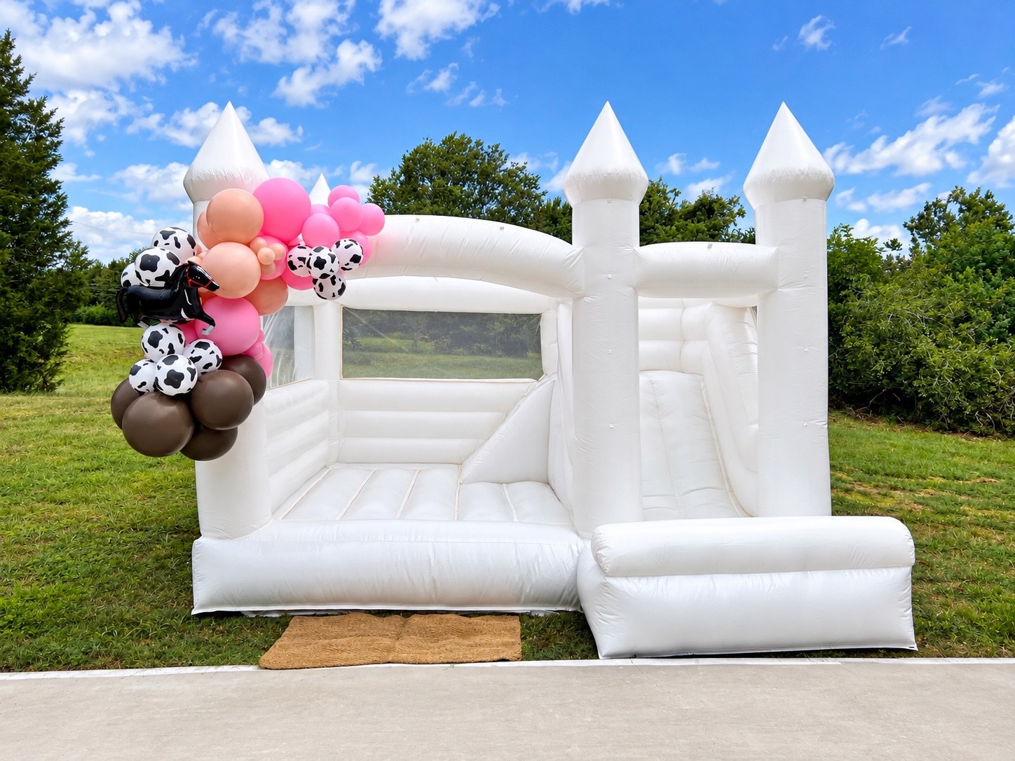 White slide castle with pink and cow-print balloons
