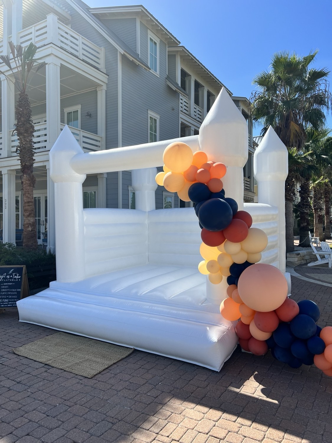 White bounce house styled with peach and navy balloons